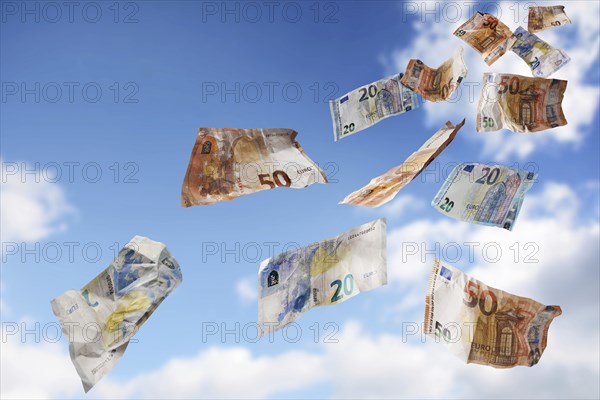 Flying money coming down from the blue sky, twenty and fifty paper banknotes in euro currency,