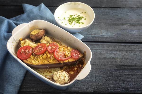 Baked half eggplant and stuffed mushrooms with garlic, ginger, onions and tomatoes in a casserole,