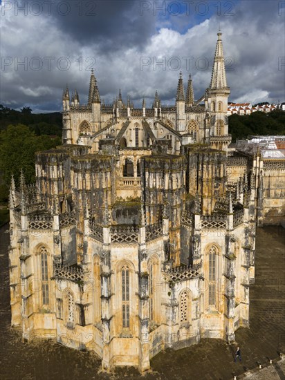 An imposing Gothic cathedral with several towers and a detailed façade under a cloudy sky, aerial