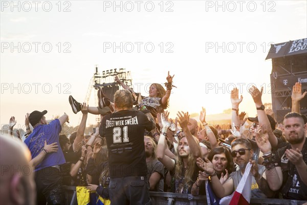 Crowdsurfers in front of the evening sun at the Wacken Open Air in Wacken. The traditional metal