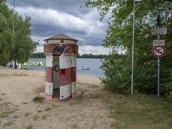 Old round red-white-ringed changing room from GDR times in the shape of a lighthouse on the shore