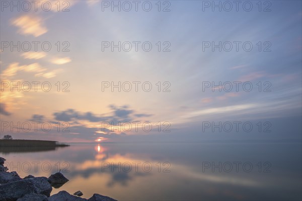 Water landscape, taken from the shore of a calm lake. View over the reflecting water to the horizon