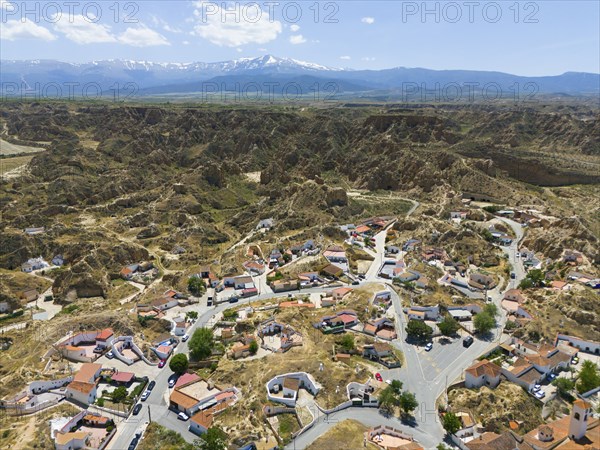 Panoramic view of a village embedded in a rocky and hilly landscape with mountains in the