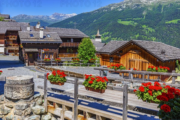 Old wooden houses with wooden shingle roofs and flower boxes in the historic centre of Grimentz,