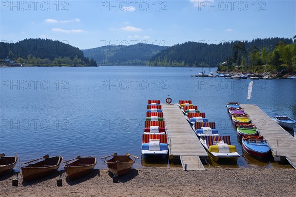 A picturesque scene with colourful pedal boats and wooden boats on a jetty in front of the