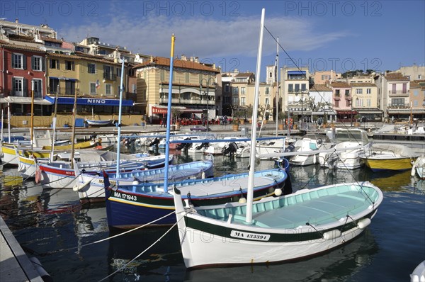 Colorful boats in a vibrant harbor with Mediterranean-style buildings under a clear blue sky,