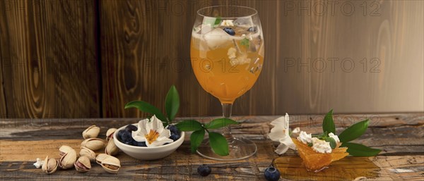 Refreshing cocktail with honeycomb, flowers, blueberries, and pistachios on rustic wooden table, AI