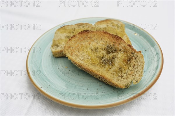 Toasted bread with olive oil, herbs and garlic salt on a blue plate, copy space, selected focus,