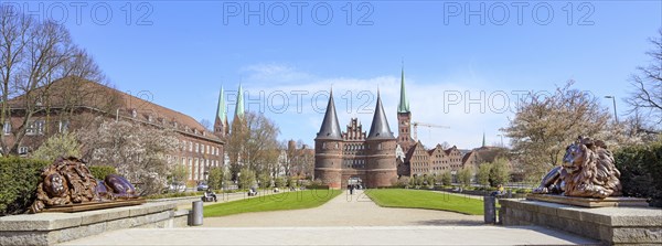 Wide panorama of the Lubeck Holstentor or Holsten gate park with two lion sculptures in front of