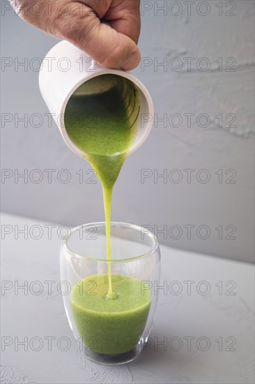 Green smoothie or soup made from wild herbs and vegetables is poured into a double-walled drinking