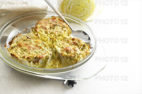 Chinese or napa cabbage gratinated in a glass casserole on a light gray table, healthy cooking,