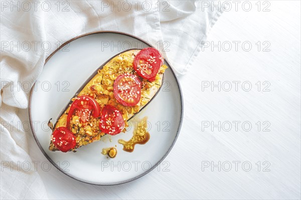 Half eggplant baked with turmeric, ginger, onions, tomatoes and sesame seed on a plate, healthy