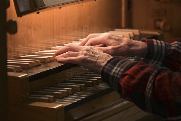 Old Hands of an organist playing on the organ keyboard also called manual, traditional musical