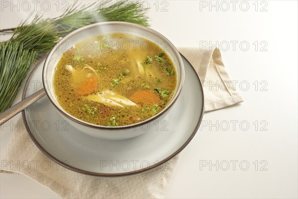 Hot steaming winter soup from chicken, vegetables and parsley in a bowl, home remedy against cold