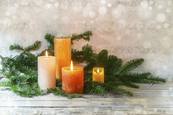 Third Advent, arrangement with four candles in orange and yellow, three are lit with a flame, fir