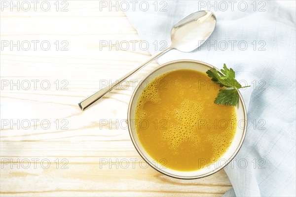 Carrot soup in a bowl on a light wooden table, healthy vegetable meal, recipe by professor Ernst