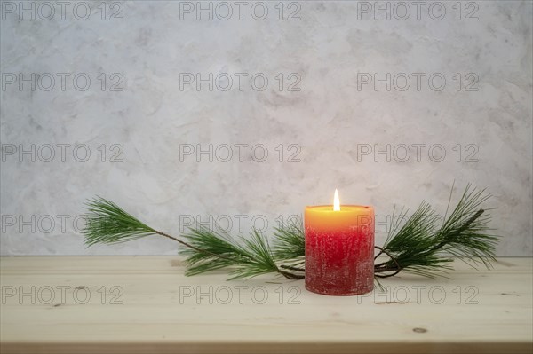 Red candle lit for the first Advent, pine branch as a simple, minimal decoration on a light wooden