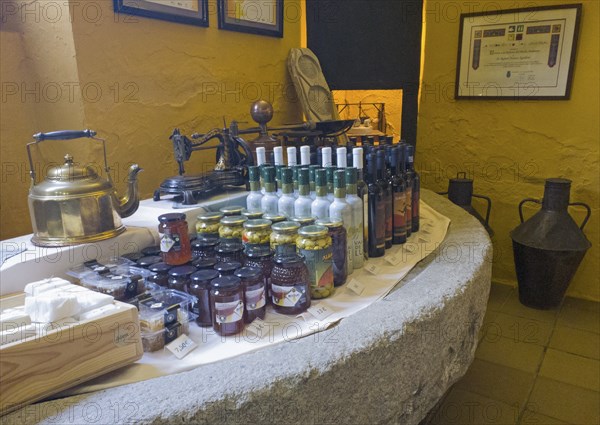 Display of products on a stone table surrounded by a yellow wall, including bottles and jars,