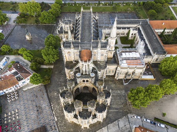 Aerial view of a Gothic abbey with elaborate architecture surrounded by trees and squares, aerial