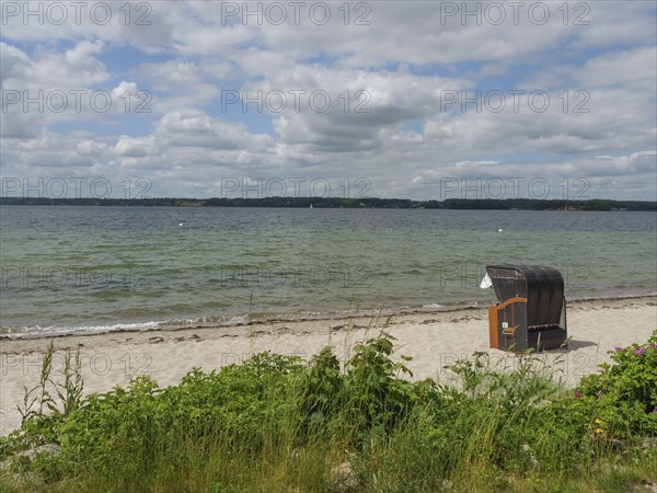 A beach with a lonely beach chair and a view of the sea under a cloudy sky, Glücksburg,