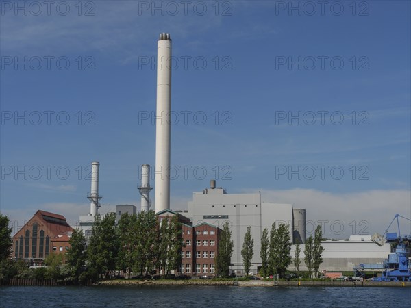 Industrial plant with chimneys and red brick buildings on the waterfront under a clear sky,