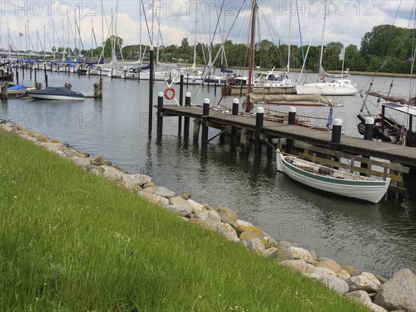 Boats at the dock in a quiet harbour surrounded by grass and a green waterfront, Kappeln,