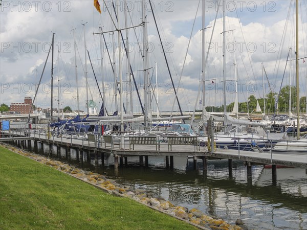 Sailboats dock at the marina in a partly cloudy sky with manicured lawn, Kappeln,