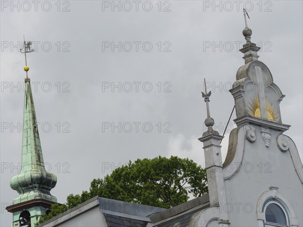 Close-up of a church with ornate spires and a weather vane in front of a grey sky, Kappeln,