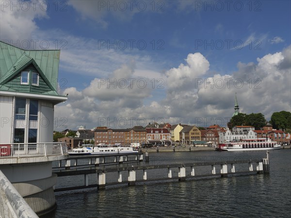 View of the town and harbour with boats and a bridge under a cloudy sky, Kappeln,