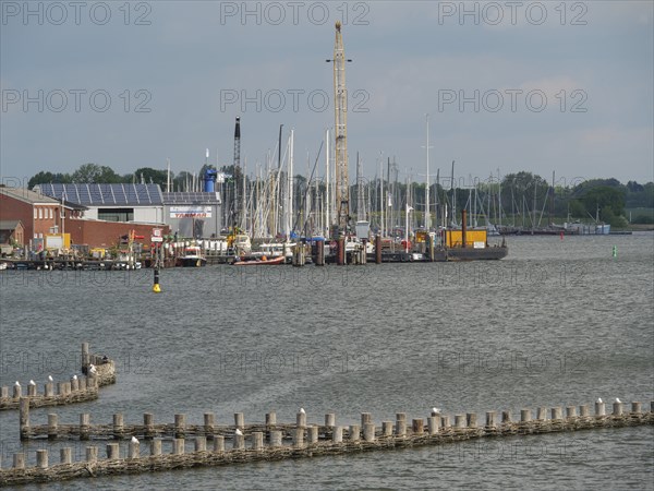 Harbour with many sailing boats and buildings along the shore under a cloudy sky, Kappeln,