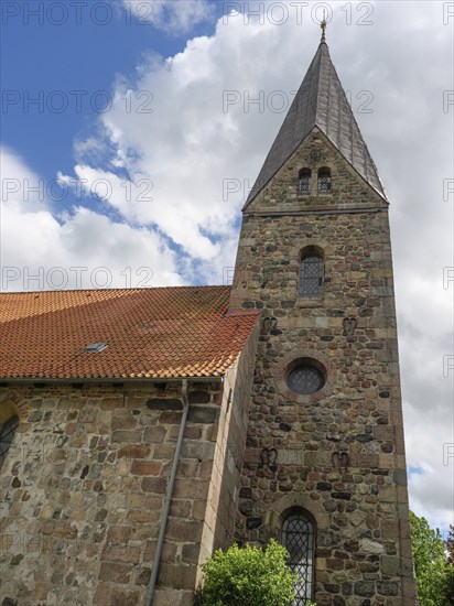 A church with a distinctive tower and red roof, under a blue sky with scattered clouds, Maasholm,