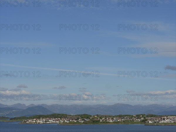 Expansive coastal landscape with a view of the sea and mountains under a slightly cloudy sky,