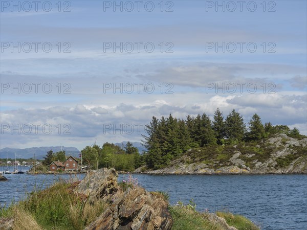Panorama of a coastal landscape with sea, islands and rocky shores under a blue sky with clouds,