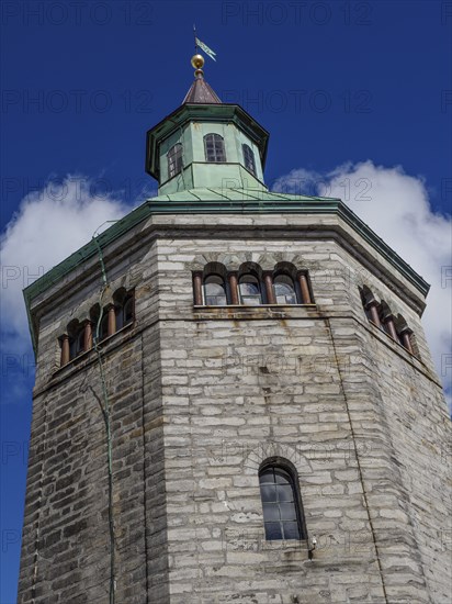 Historic stone tower with striking clock and flag. Bright blue sky in the background, Stavanger,