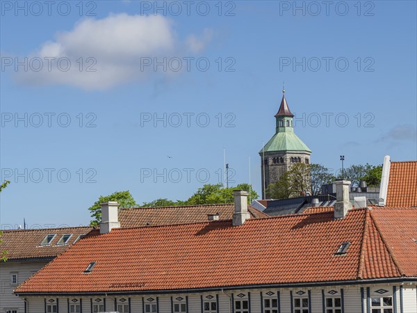 Historic tower and building with tiled roofs under a blue sky with light clouds, Stavanger, Norway,