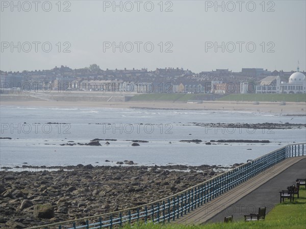 A stretch of coastline with a promenade and a view of a town in the background, Newcastle, England,