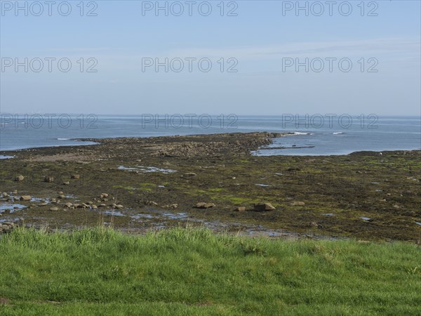 Clear views of the sea, rocks and a calm coastline under a blue sky, Newcastle, England, United