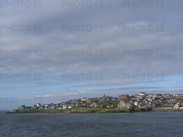 Coastal landscape with houses under cloudy sky and neighbouring sea, Lerwick, Shetlands, Scotland,