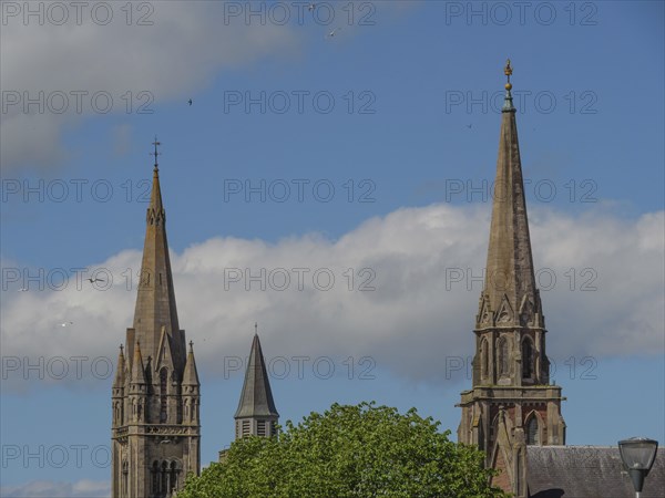 Buildings with high church towers and gothic architecture under a slightly cloudy sky, inverness,
