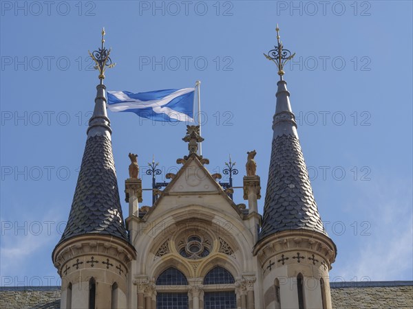 Close-up of a castle with Scottish flag, distinctive towers and detailed architecture under a clear