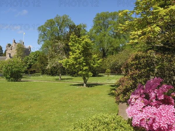 A beautiful garden in spring with flowering bushes and trees in front of a castle, inverness,