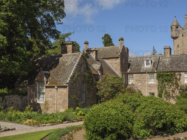 An old building with castle and garden, surrounded by stone walls and dense vegetation, inverness,