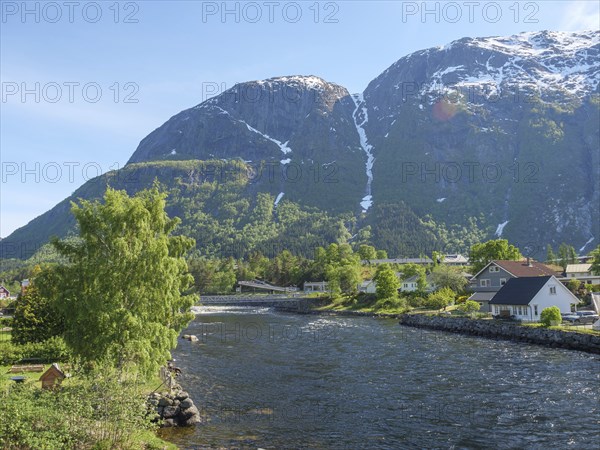 An idyllic village on the riverbank, surrounded by green nature and high mountains in the