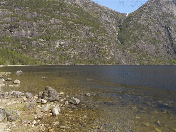 Lake with clear water, surrounded by high mountains and dense vegetation, quiet and peaceful