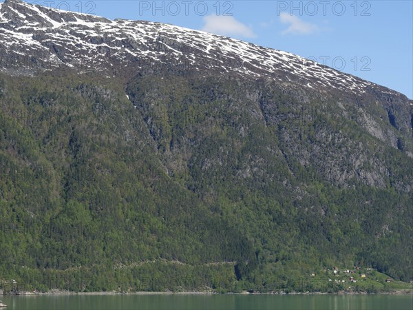 High mountain landscape with snow-capped peaks and green mountain slopes under a clear sky,