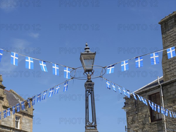 Lamp with hanging Scottish flags in front of a historic building and blue sky, Lerwick, Shetlands,