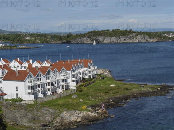 White houses with red roofs on the coast. Tranquil seascape with sailing boat and rocks in the