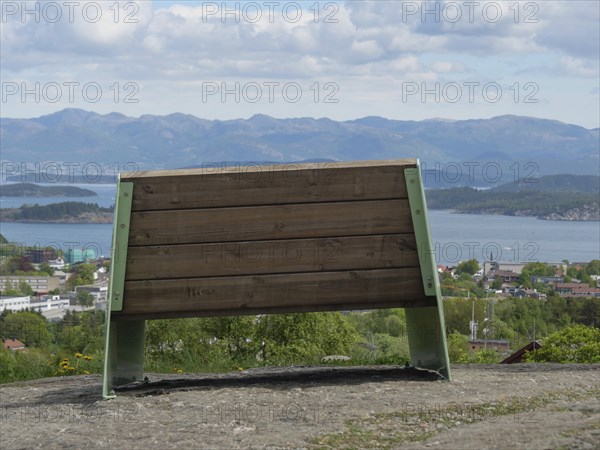 A wooden bench with a view of a picturesque mountain landscape under a cloudy sky, Stavanger,
