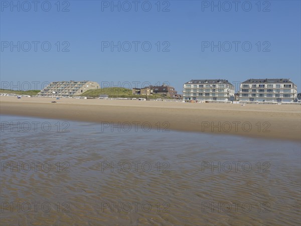 Building on a vast sandy beach with calm sea and blue sky in the background, de haan, belgium