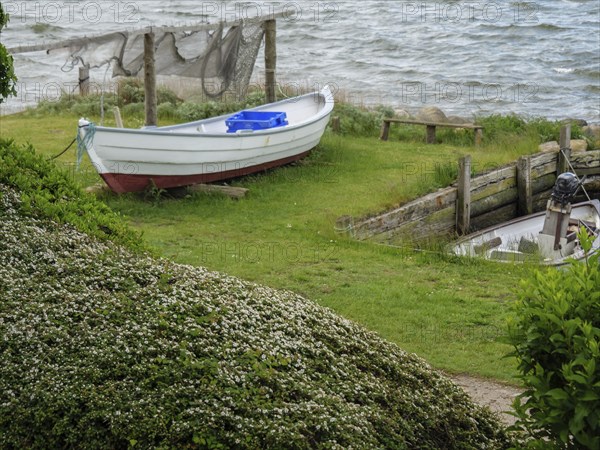 Small boat on a green bank next to the water with nets in the background, Maasholm,